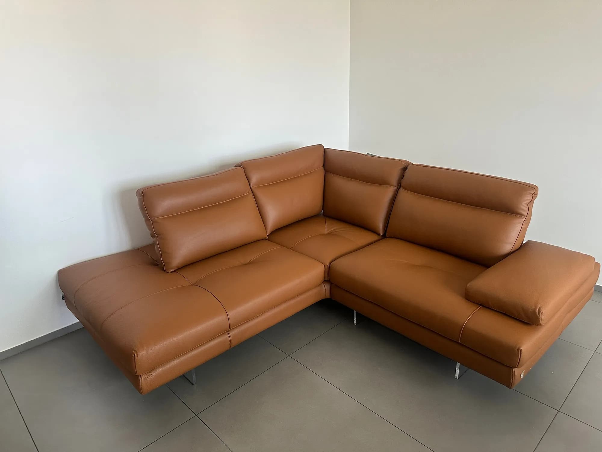 Un divano angolare in pelle color cuoio in una stanza vuota, pronto per il trasporto